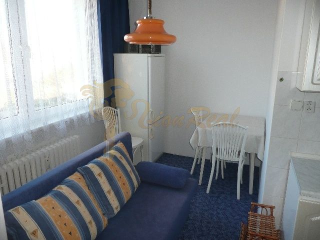 A room with a blue couch and an orange lamp in a two-room apartment.