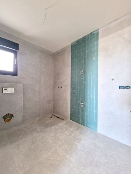 A bathroom in a 3-room apartment with gray tiles and a blue mosaic on the wall.