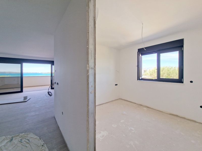 Partially finished interior of a 3-room apartment with a sea view, floor with wooden decor.
