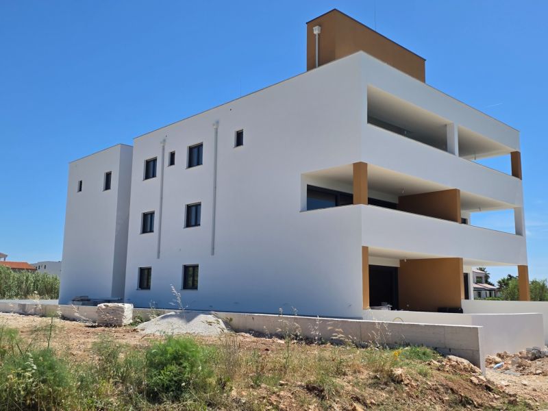 White apartment building with balconies in Privlaka against the blue sky, 3-room apartment.