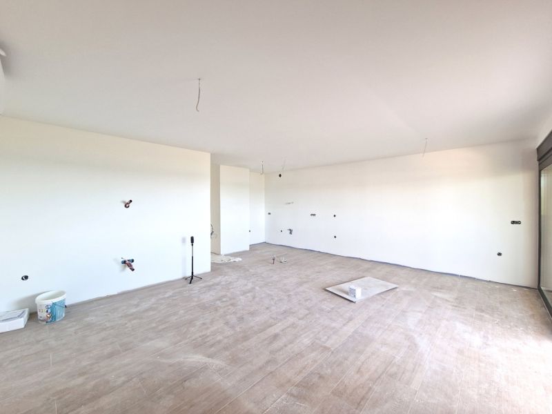 A spacious room of a 3-room apartment with a wooden decor floor and a large window.