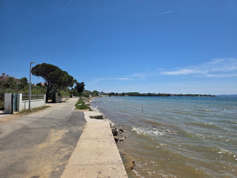 The coastal road in Privlaka runs along the sea in sunny weather.