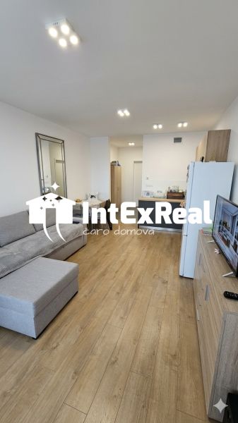 Living room in a one-room apartment with a corner sofa and a floor with a wooden decor.