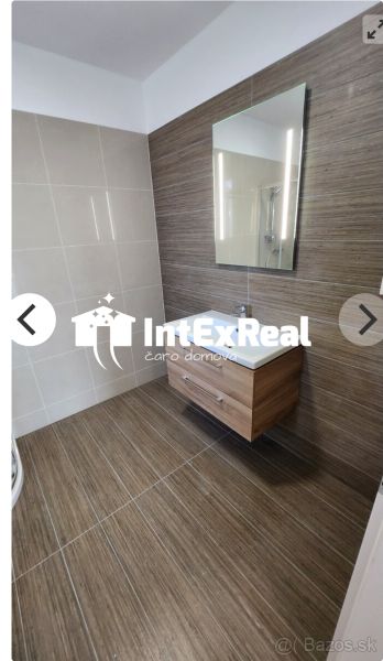 A bathroom in a studio apartment with a floor and walls in wooden decor.