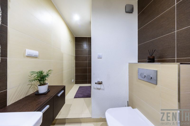A bathroom in a 3-room apartment with brown and beige tiles and green decorations.