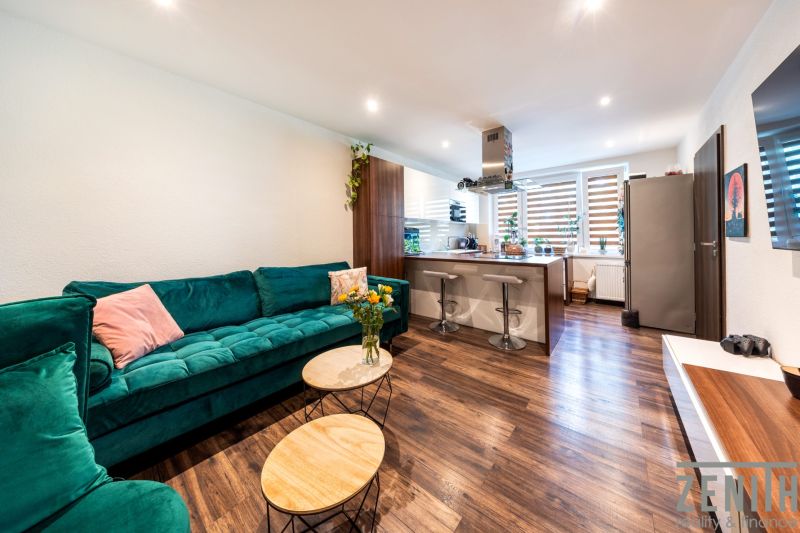Living room with a kitchenette in a 3-room apartment, wooden decor flooring, green sofa.