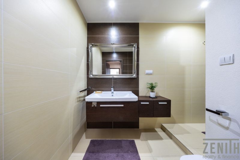 A bathroom in a 3-room apartment with a white sink, dark wood decor, and a mirror.