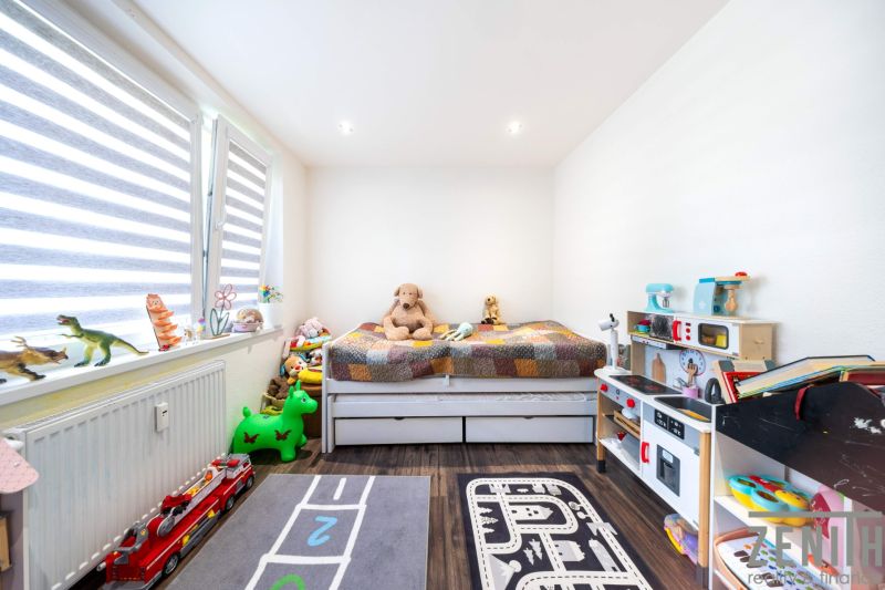 Children's room with toys and a bed, wooden decor flooring in a 3-room apartment.