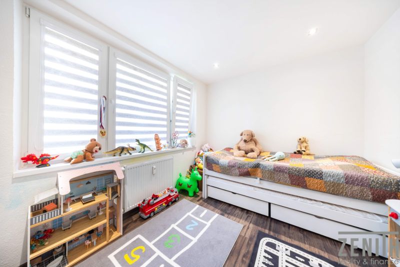 Children's room in a three-room apartment with a wooden decor floor, full of toys and teddy bears.