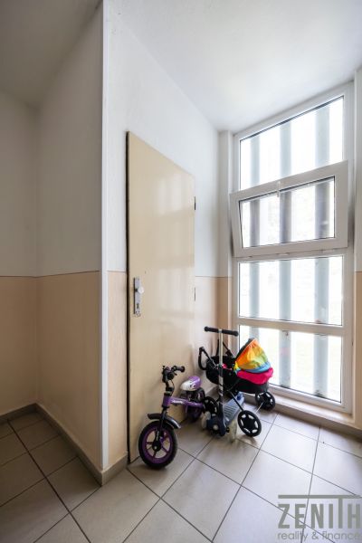 A hallway with a children's bicycle by the window and door in a 3-room apartment.