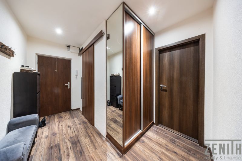 Entrance hallway with wood-patterned flooring in a 3-room apartment, mirrored wardrobe and light.