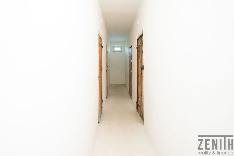 Hallway in a 3-room apartment with white walls and doors to the rooms.