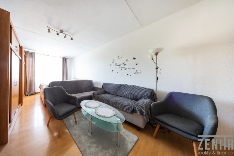 Living room with wood-patterned flooring in a 3-room apartment, gray sofas, glass table.