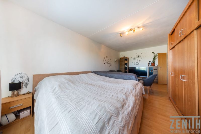 A bedroom in a 3-room apartment with a built-in wardrobe and flooring with a wood decor.