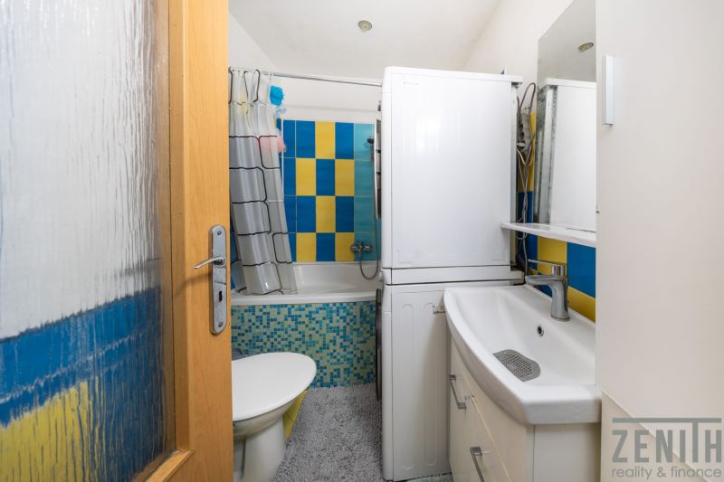 A bathroom in a 3-room apartment with colorful tiles and a washing machine.