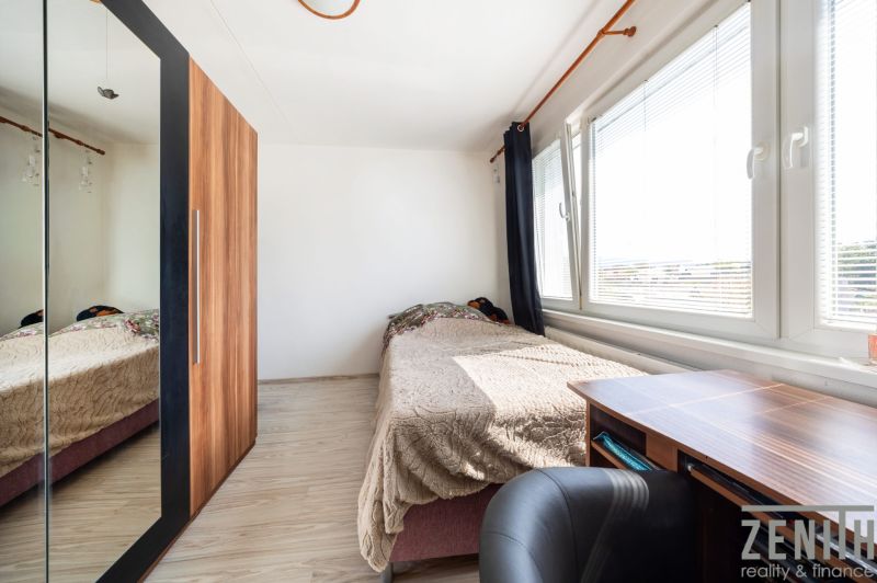 A room with a bed, a desk, and a wardrobe with a mirror in a three-room apartment.