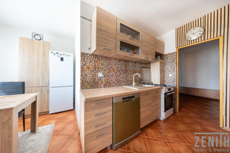 A kitchen in a 3-room apartment with a wood-patterned floor and ceramic tiles.