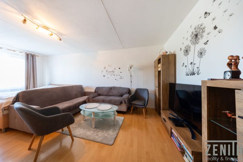 Living room with sofas, an armchair, a television, and a wooden decor floor in a 3-room apartment.