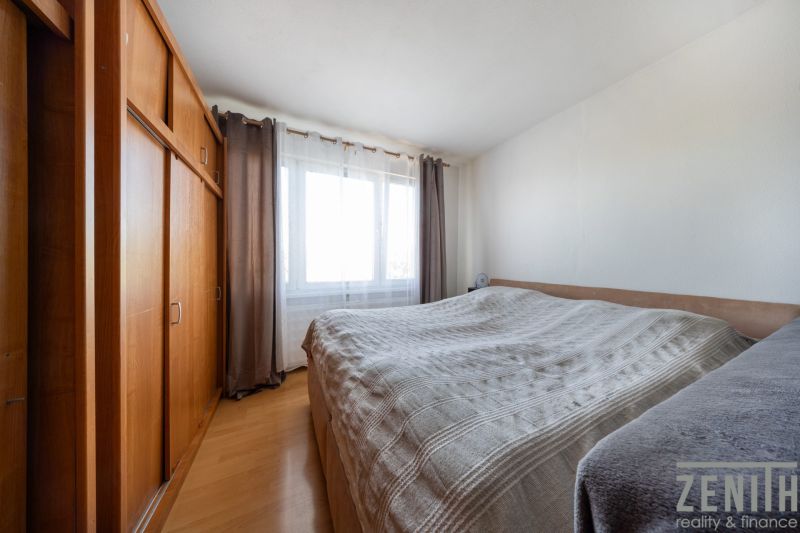A bedroom with a bed, a large wardrobe, and a floor with a wooden decor in a 3-room apartment.