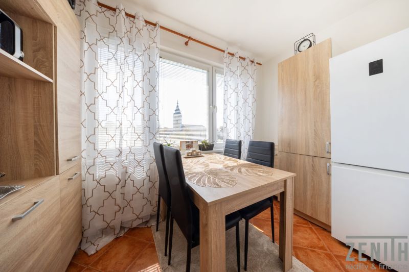 A dining table with four chairs in a three-room apartment, curtains with a geometric pattern.