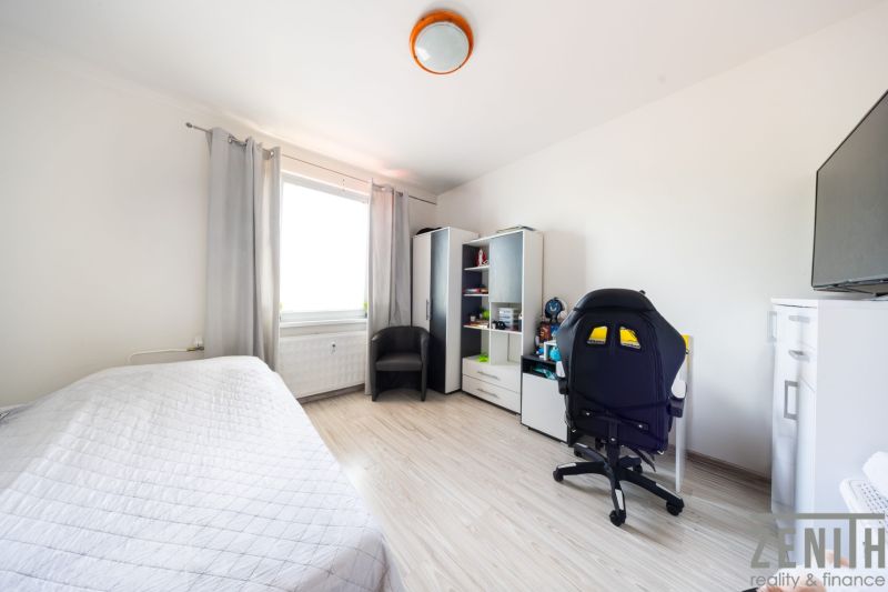 A bright room in a 3-room apartment with a wooden decor floor and a desk.