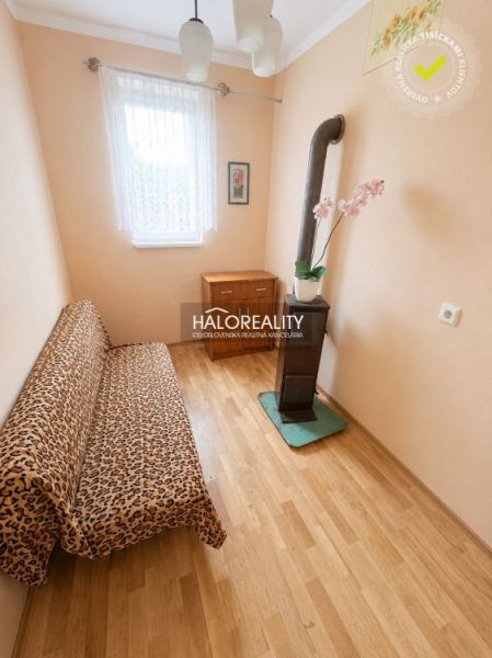 A room in a family house with a wooden decor floor, a sofa, and a stove.