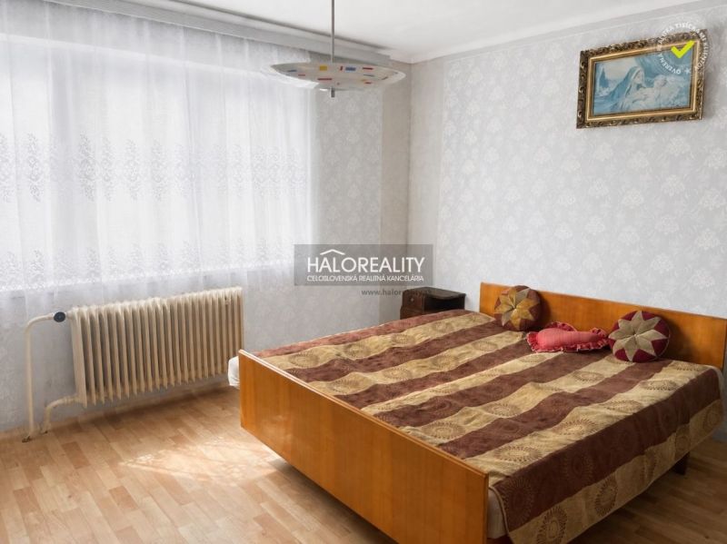 Bedroom in a family house with a wood-patterned floor and a radiator by the window.