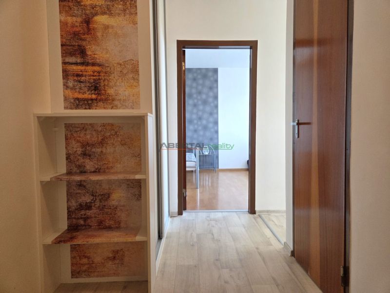 A hallway with a wooden decor floor in a one-room apartment. Entrance to another room.