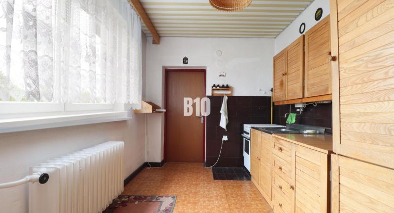 A kitchen in a family house with wooden decor and white curtains.