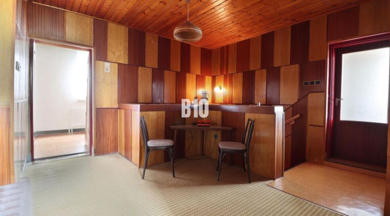 Interior of a family house with a wooden ceiling, panel walls, and two chairs.
