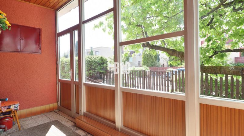 A glazed veranda with a view of the yard in a family house.