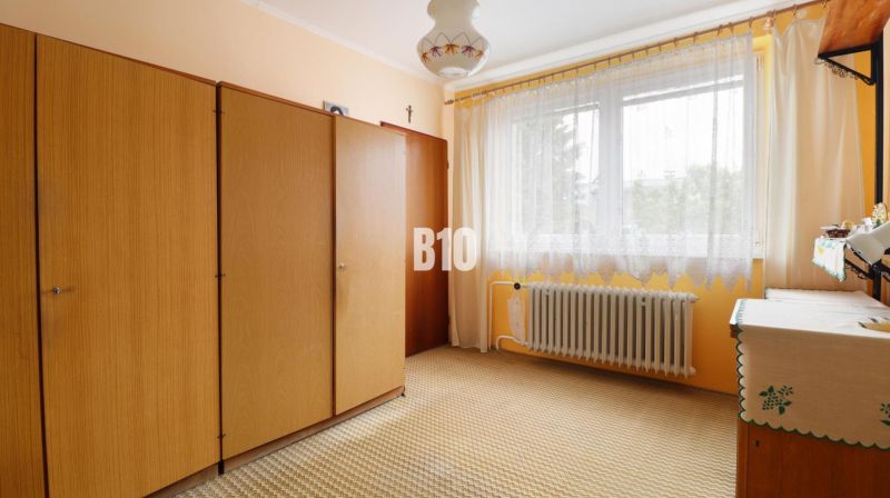 A room in a family house with a wardrobe, curtains, and a radiator.