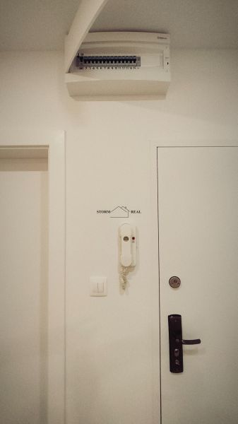 A white interior with an electrical panel and an intercom in a 4-room apartment.