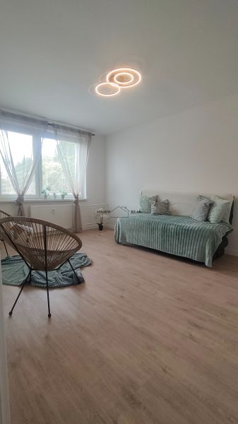A room in a 4-room apartment with a wooden decor floor and light furniture.