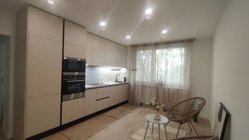 Kitchen in a 4-room apartment with a wooden decor floor and a large window.
