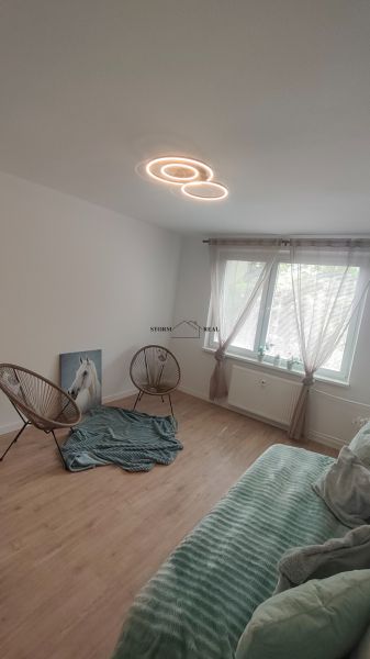 A room in a 4-room apartment with a wooden decor floor, armchairs, and a sofa.
