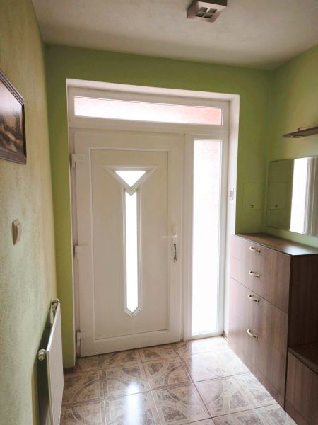 Entrance door in a family house with a white frame and decorative tiles.