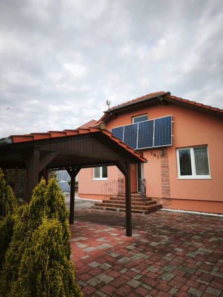 A family house in Martin nad Žitavou with solar panels and a gazebo on the terrace.