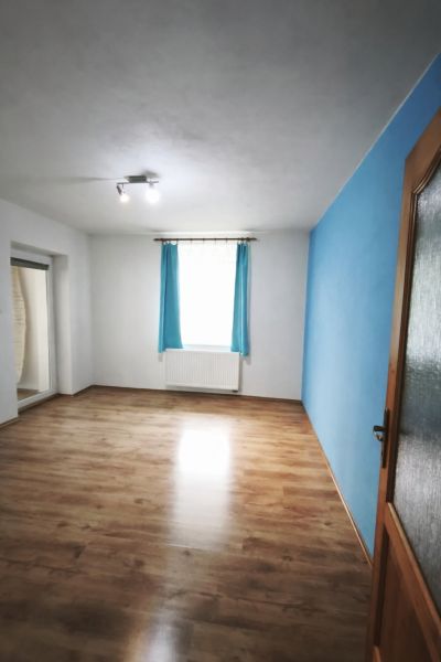 A room in a family house with a blue wall and a wooden decor floor.