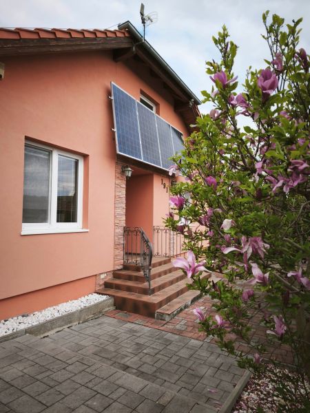 A family house on Hlavná Street in Martin nad Žitavou with solar panels and a magnolia.