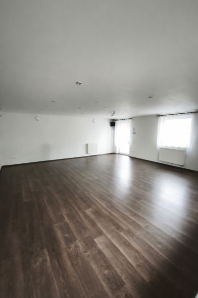 A spacious room in a family house with a wooden decor floor and white walls.