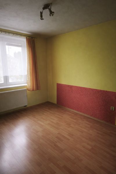 A room in a family house with a wooden decor floor and a colorful wall.
