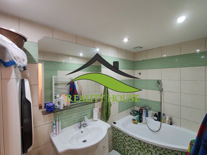 The bathroom of a 3-room apartment with a bathtub, sink, and tiles in shades of green.
