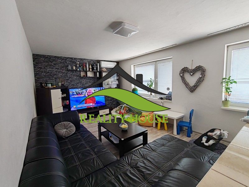Living room in a three-room apartment with a sofa and TV, floor with wood decor.