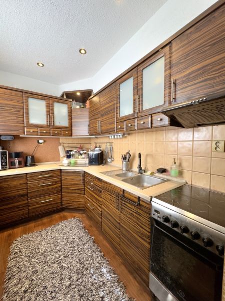 A kitchen in a 4-room apartment with a wood-patterned floor and appliances.