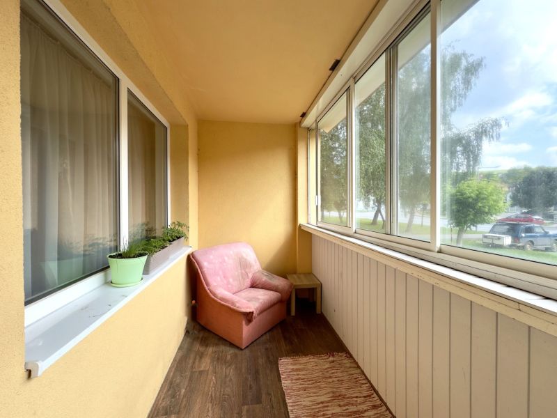 Balcony of a 4-room apartment with seating and flooring with a wooden decor.