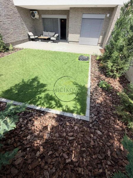 Garden of a 2-room apartment in Galanta with a grassy area and terrace seating.
