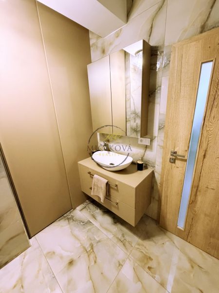 Bathroom with cabinet and sink, marble-patterned tiles, wooden door.