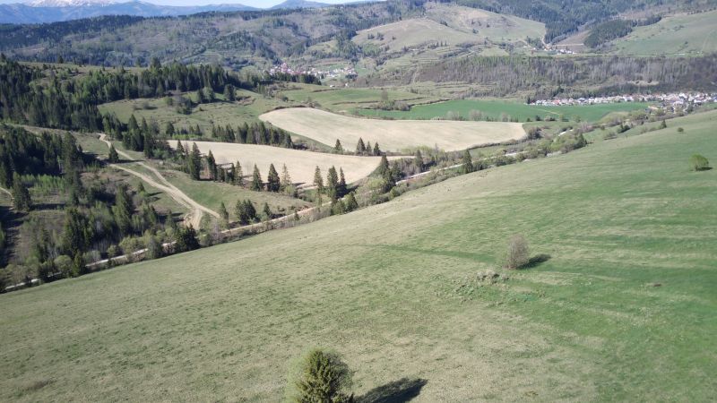 A hilly landscape in Čierny Balog with agricultural and forest lands full of trees and meadows.