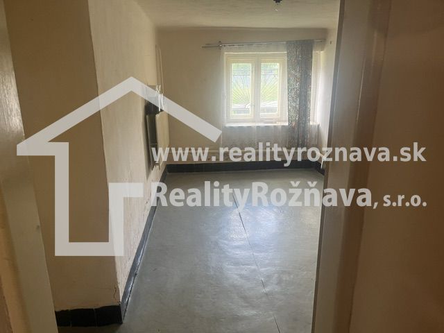 A room in a family house with a concrete floor and a window with incoming light.